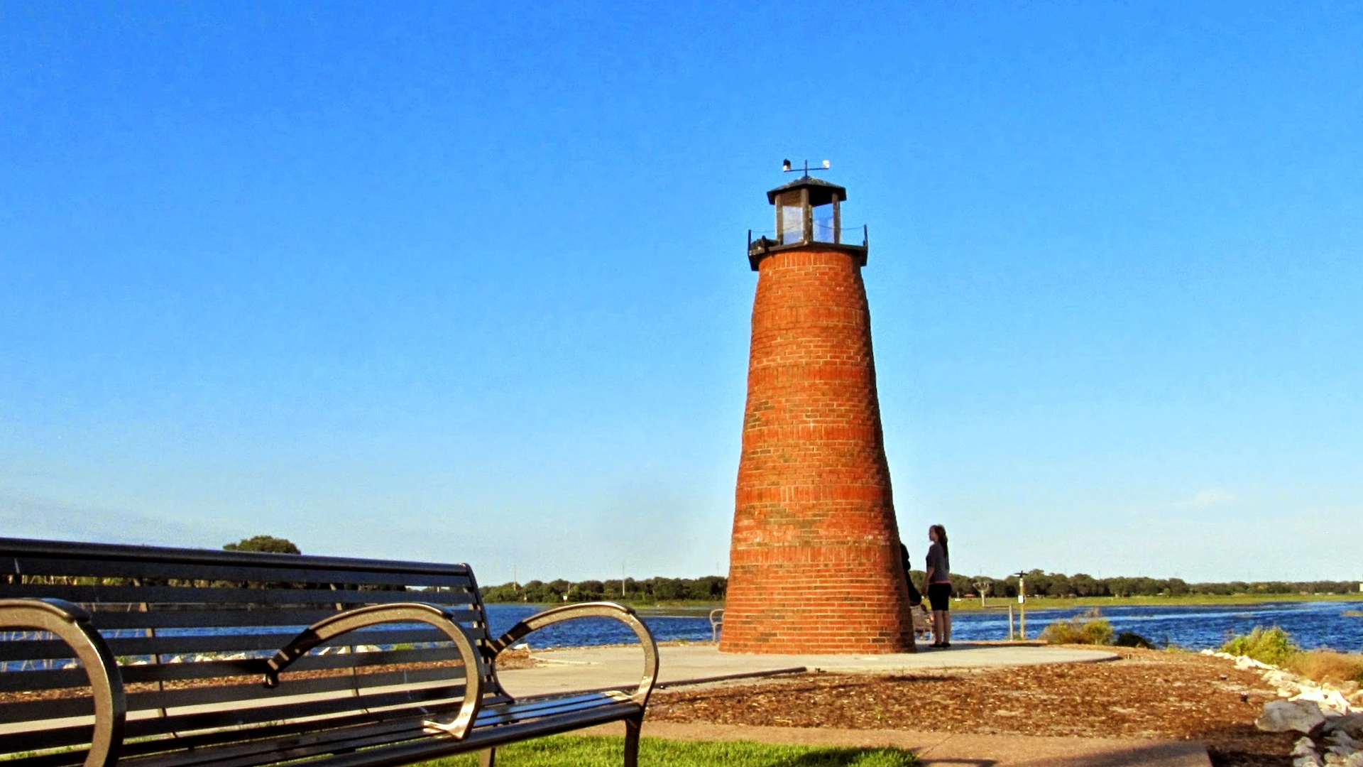 Brick lighthouse on the Kissimmee lakefront, with a bench in the foreground