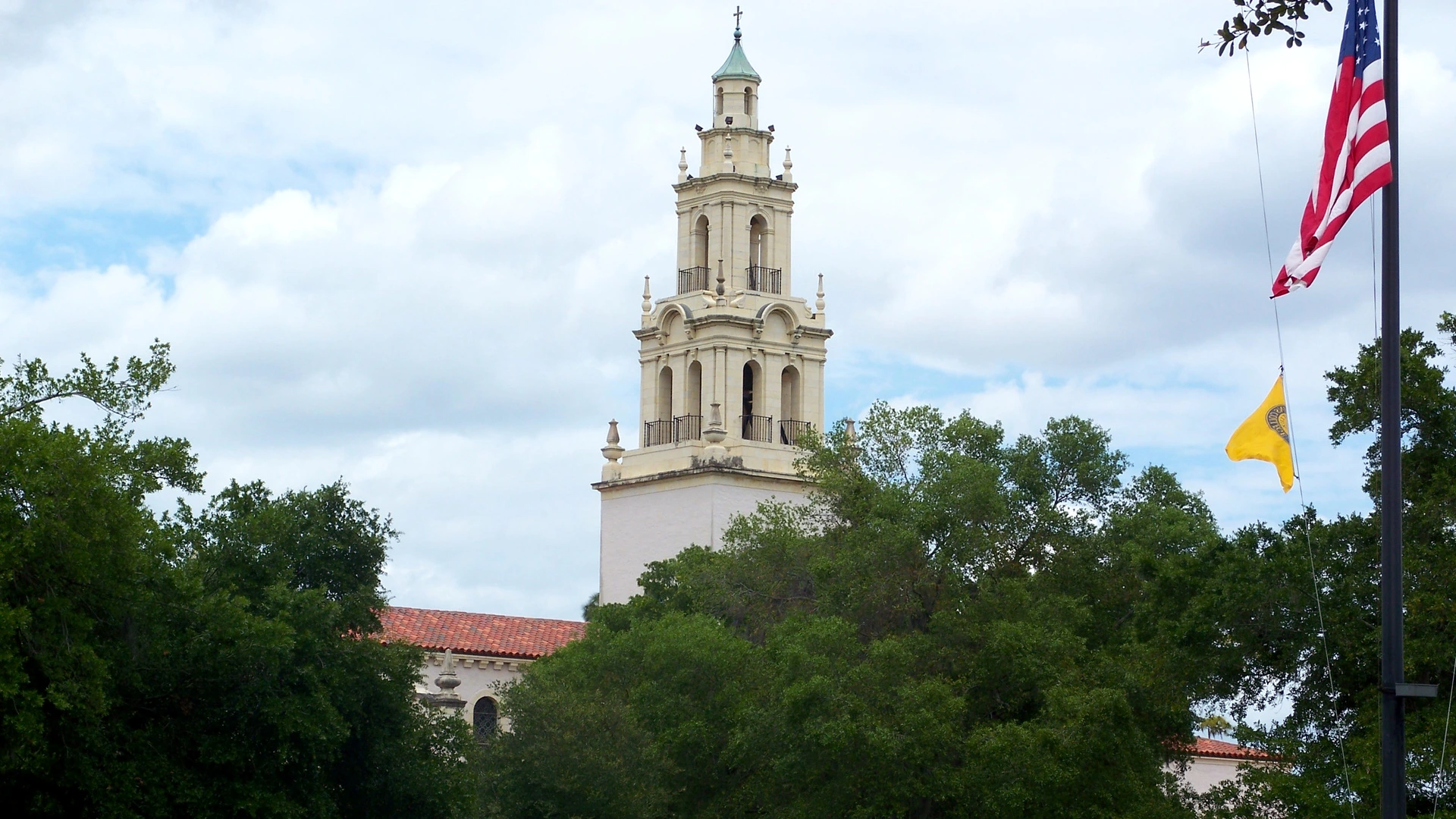 Bell tower rising above the trees in Winter Park, with an American flag